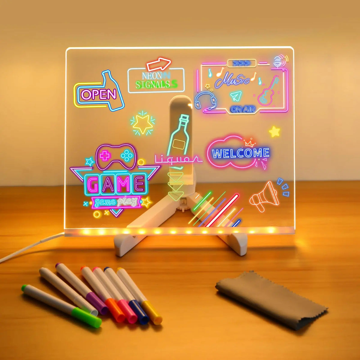 An LED glowing message board displays neon signals and a welcome message next to a set of seven colored pens.