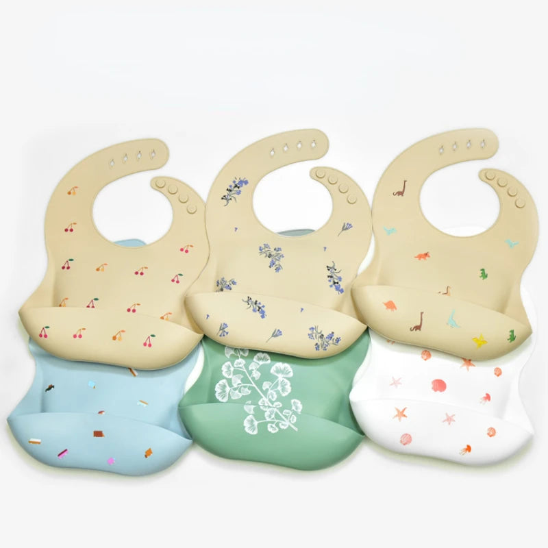 A set of waterproof silicone baby bibs in various pastel colors with catch pockets for babies.