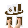 A set of white cards showing handprints and footprints on a dark brown background, with a baby's hand and foot visible below.