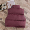 A maroon quilted down vest for kids lying on a wooden floor next to a photo frame.