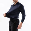 Un hombre con camisa formal azul marino oscuro y pantalones negros.