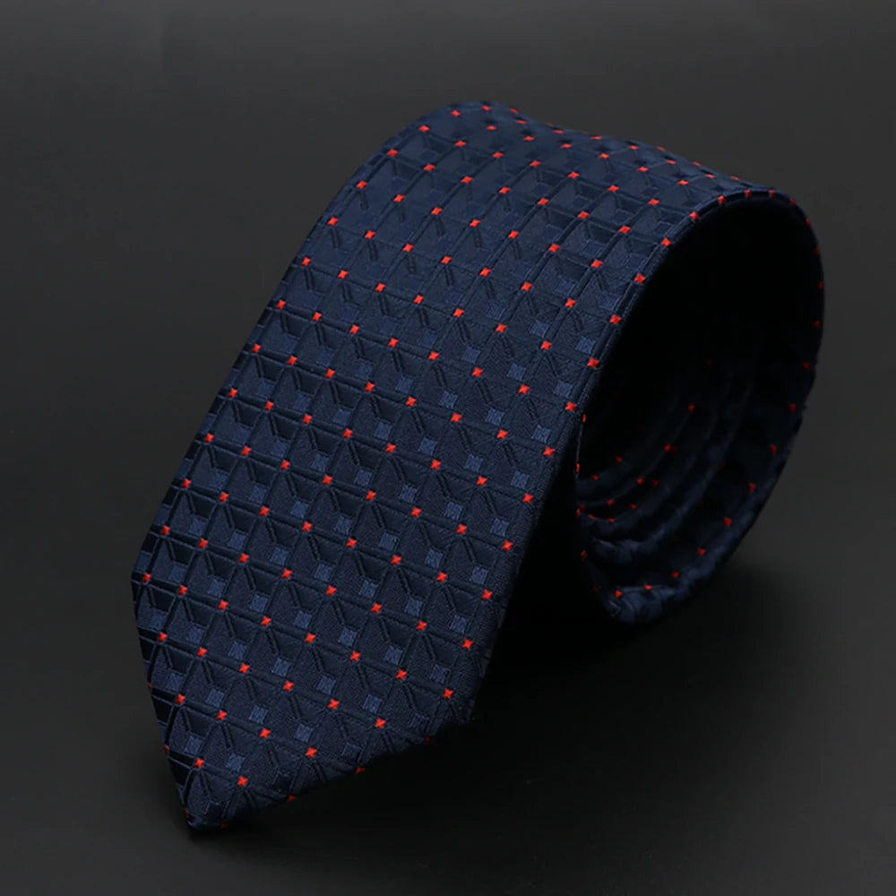 Corbata azul oscuro con diseño geométrico, enrollada sobre fondo oscuro.