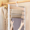 Main accrochant un vêtement en tissu gris à un cintre à pantalon blanc à clips antidérapants.