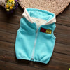 A light blue fleece zip-up vest with a cream lining and a yellow cartoon patch on a wooden surface.