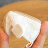 A hand holds a pair of soft non-slip baby first walker shoes in a beige color.