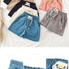 A close-up of blue kids beach shorts with elastic waist and a white tag on the fabric.