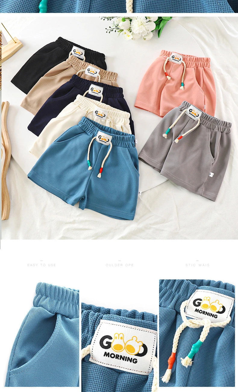 A close-up of blue kids beach shorts with elastic waist and a white tag on the fabric.