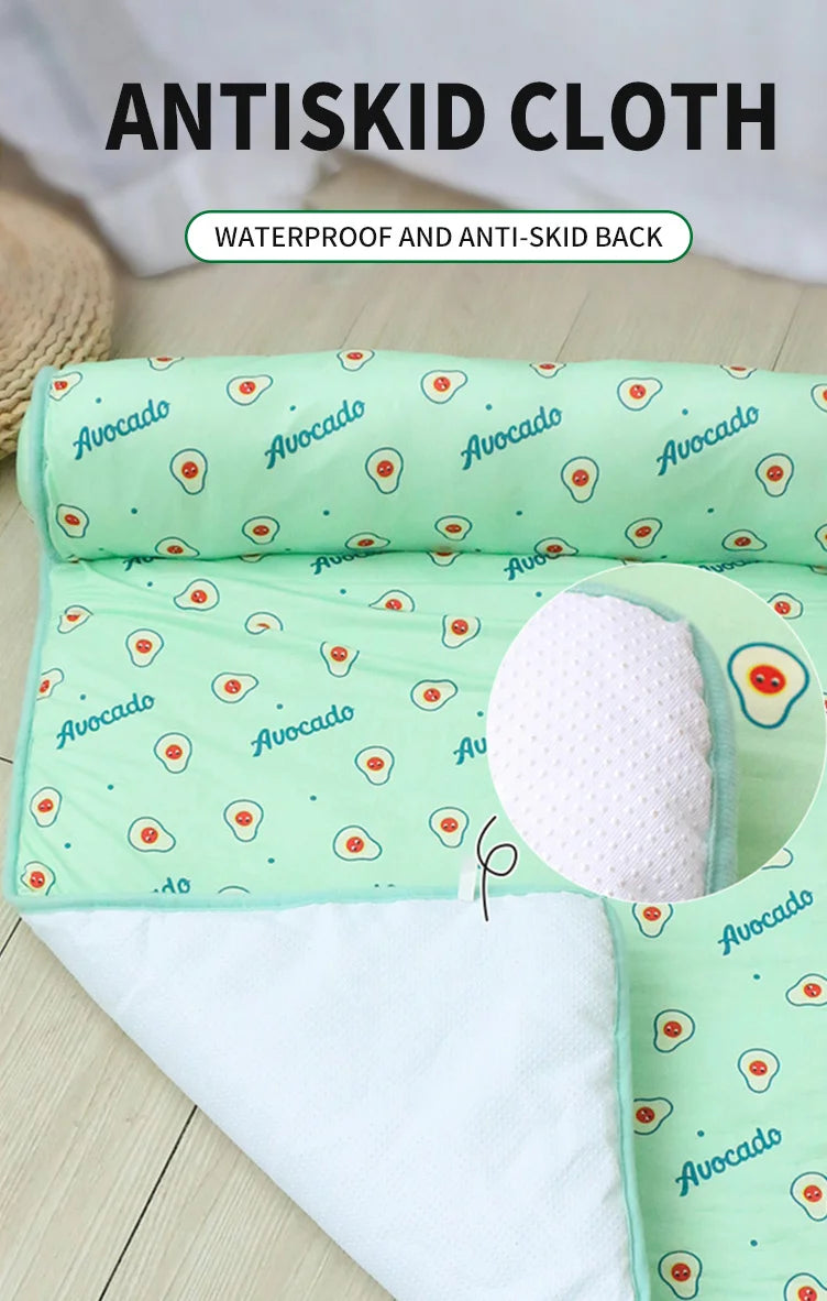 A light green anti-skid cloth mat with avocado print and a white layer shown on a wooden surface.