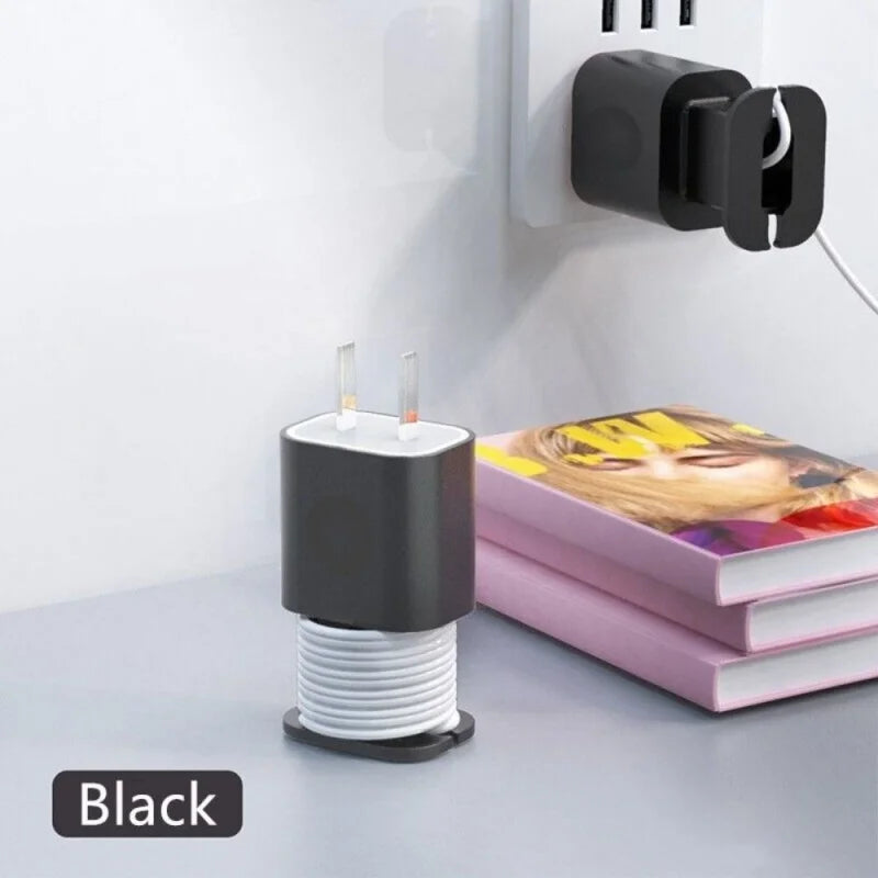 A black silicone charger protector and cable organizer with two charging tips mounted on a white wall.