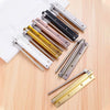 A collection of stainless steel automatic door closers with various colored finishes arranged on a light wooden surface.
