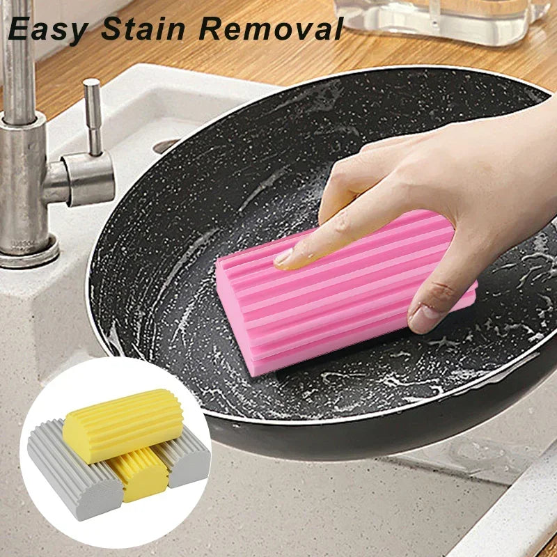 Una mano usa una esponja limpiadora de PVA rosada para quitar manchas de un plato negro en un fregadero de cocina.