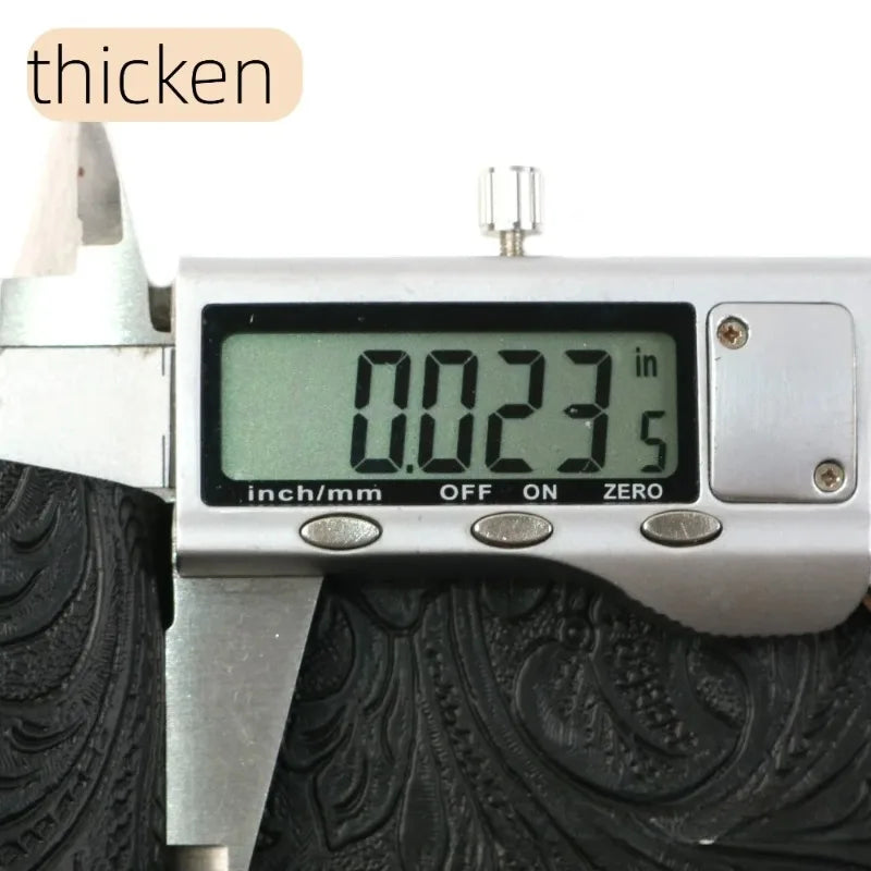 A digital caliper measures 0.023 inches on a vintage floral textured faux leather fabric.