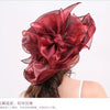 A deep red satin flower-shaped headpiece or fascinator worn on a person's hair.