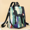 A women's anti-theft water-resistant nylon backpack with a multicolored abstract design on a light background.