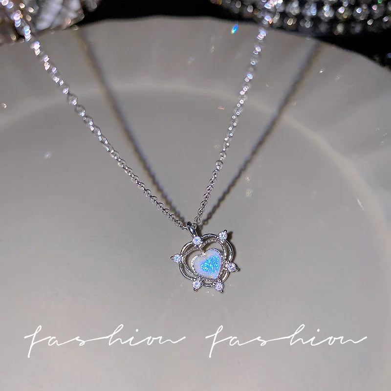 Silver heart pendant necklace featuring a blue iridescent gemstone surrounded by crystal accents.