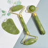Juego de rodillo de jade natural y herramientas gua sha en piedra verde claro con acentos dorados para masaje facial.
