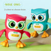 A pink and blue musical dancing owl and duck toy with lights for kids sitting on a green surface.