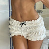 A woman wearing white ruffled tiered shorts with a black bow detail.