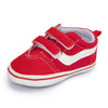 A pair of red and white striped canvas baby sneakers with an anti-slip sole.
