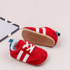 A pair of red and white Adidas baby first walker shoes with a brown anti-slip sole resting on a light background.