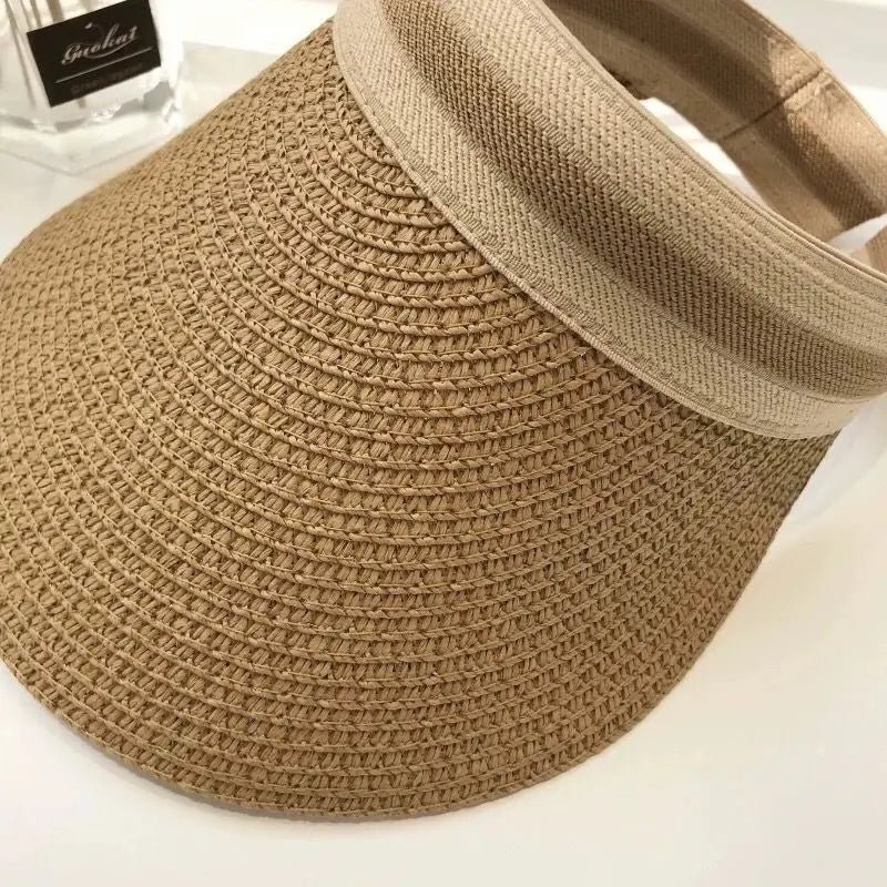 A close-up view of a woven straw sun hat with a wide brim in a natural beige color.