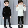 Two young children wearing black and white knit turtleneck sweaters and black pants.