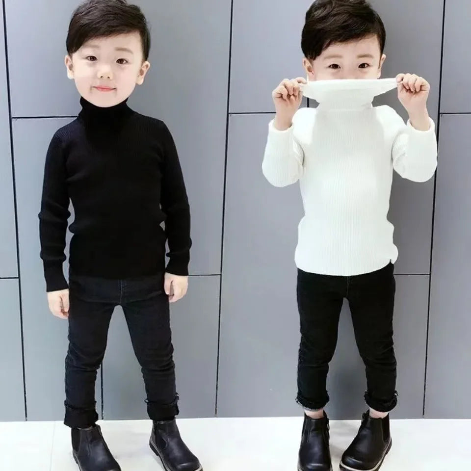 Two young children wearing black and white knit turtleneck sweaters and black pants.