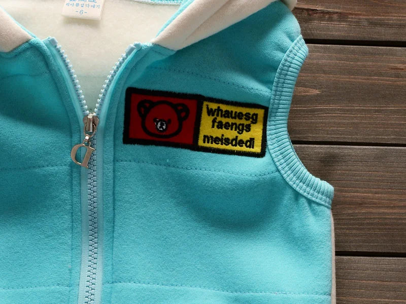 A light blue fleece pajama top with a zipper and a black and yellow embroidered patch featuring a bear face.