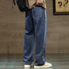 A pair of dark indigo men's baggy straight-leg denim jeans with a drawstring waist worn by a person.