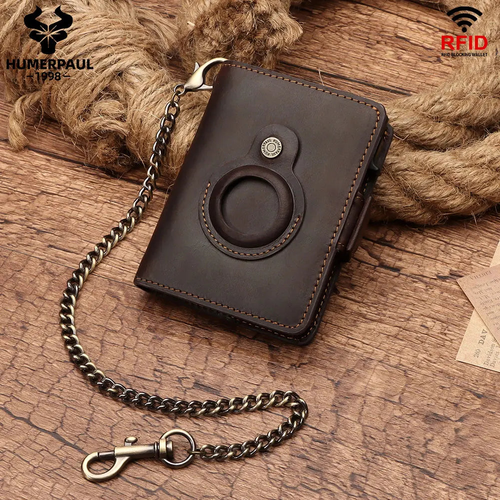 A dark brown leather wallet with a metal chain attached, featuring RFID blocking and an AirTag holder, resting on a wooden su