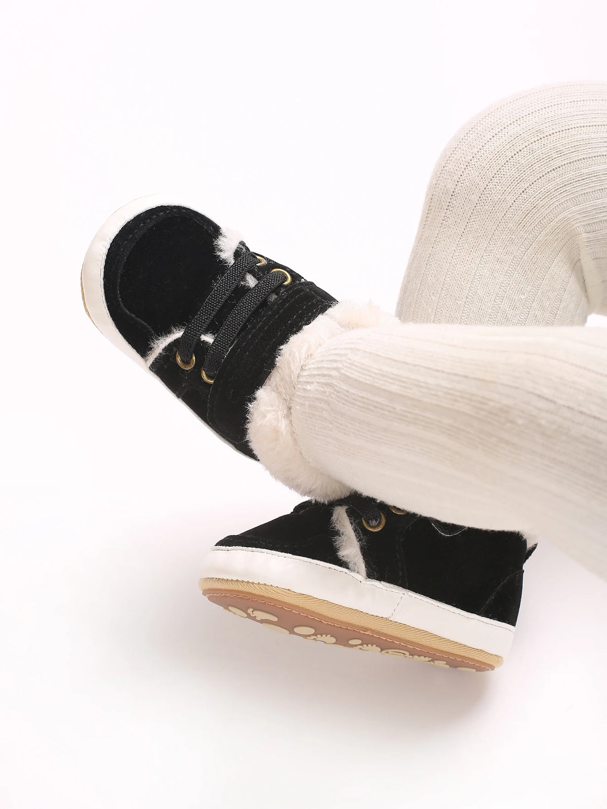 A close-up of a pair of black baby winter snow boots with white fuzzy trim and white canvas fabric.