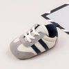 A pair of baby first walker shoes featuring light gray and cream colors with navy blue stripes.