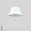 A white wide-brim bucket hat with thin white ties is shown against a light gray background.