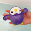 A purple and yellow suction cup bath basketball hoop toy is held in a hand above water.