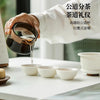 Une main verse du thé d'une théière en céramique dans trois petites tasses blanches sur une table en bois.