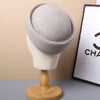A beige straw pillbox sun hat displayed on a mannequin against a light background.