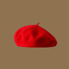 A bright red classic wool beret hat viewed from above against a neutral background.