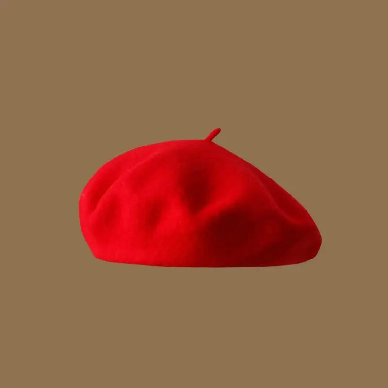 A bright red classic wool beret hat viewed from above against a neutral background.
