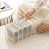 A wooden organizer box filled with neatly folded gray and beige underwear and socks.