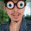 A person wearing large, round novelty glasses with blue irises and a mustache is looking at the camera.
