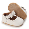 A pair of white soft non-slip baby first walker shoes with light brown soles and a leather strap.