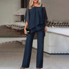 En kvinne modellerer et marineblått todelt sett med en off-shoulder topp med gjennomsiktige ermer og vide bukser.