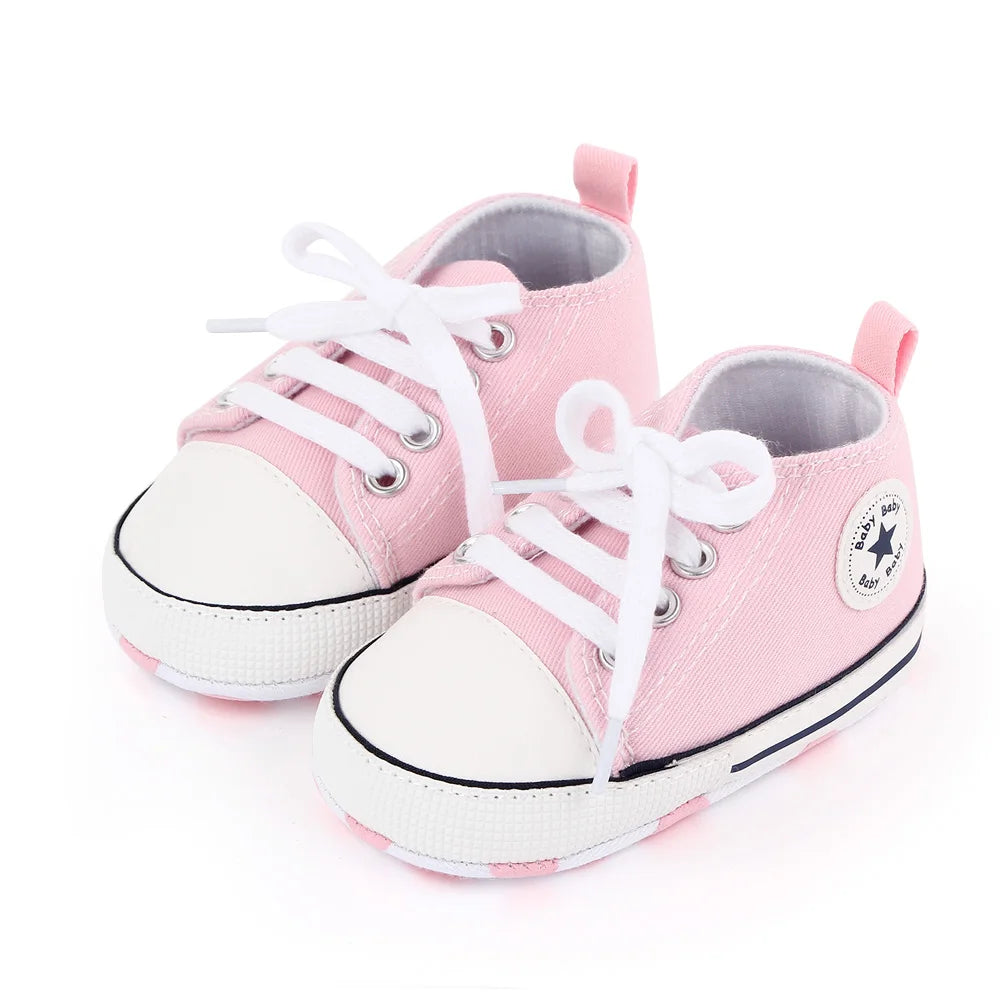 Pink canvas baby sneakers with white laces and non-slip soles