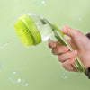 A hand holds a green pet bath brush with a silicone dispenser, spraying water and bubbles against a light green background.