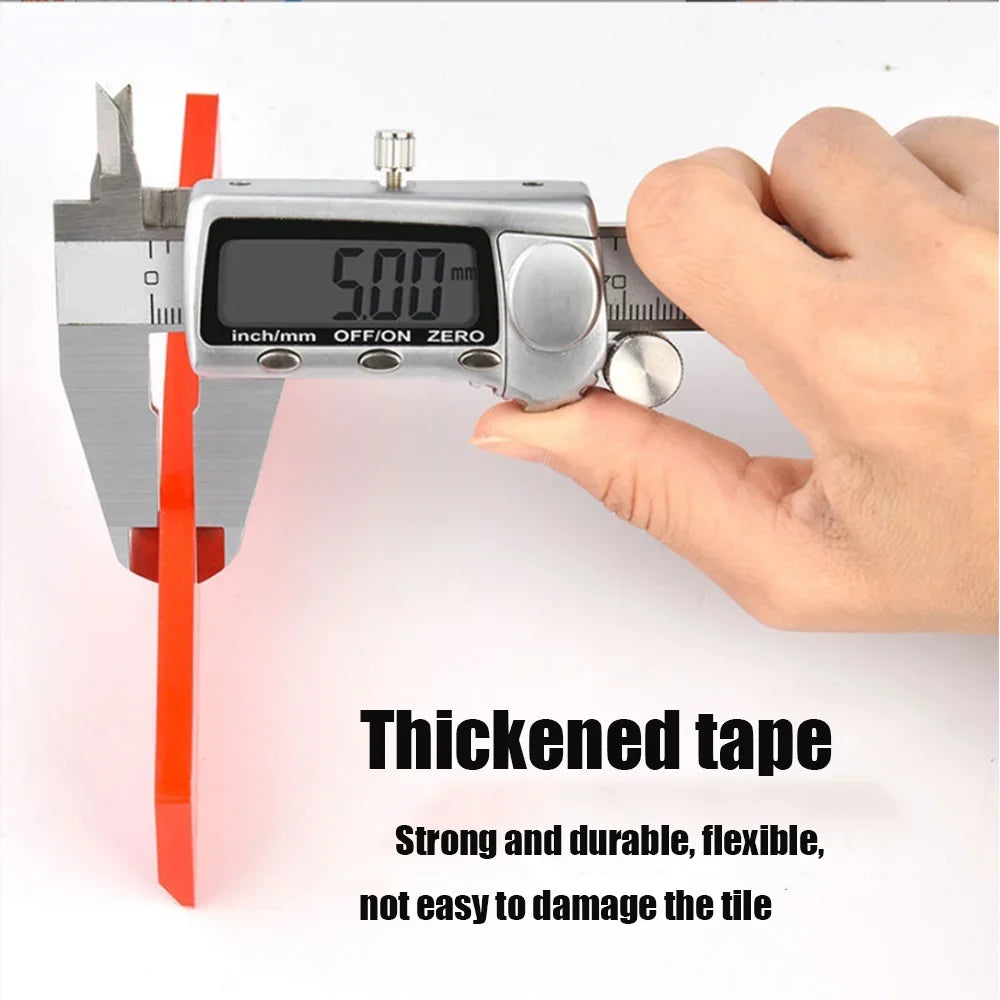 A hand holds a silver tile gap filling and cleaning scraper set with a digital measurement display.