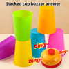 A stack of colorful plastic cups in green, orange, blue, and pink, used for a stacking game.