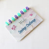 A pink marble binder with 52 purple and teal colored weekly markers for a money saving challenge.