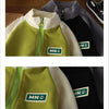 A close-up of a kids color block zip-up jacket with a lime green fleece lining and gray exterior.