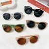 A collection of sunglasses in black, white, olive green, and rose gold tones displayed on a white surface.