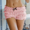 A close-up shot of a woman wearing pink ruffled tiered shorts with a black bow detail.